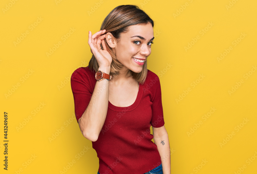 Young blonde girl wearing casual clothes smiling with hand over ear listening an hearing to rumor or gossip. deafness concept. Young blonde girl wearing casual clothes smiling with hand over ear listening an hearing to rumor or gossip. deafness concept.