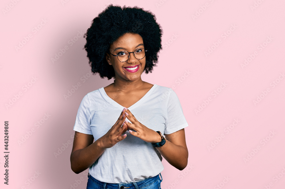 Young african american woman wearing casual white t shirt hands together and fingers crossed smiling relaxed and cheerful. success and optimistic Young african american woman wearing casual white t shirt hands together and fingers crossed smiling relaxed and cheerful. success and optimistic