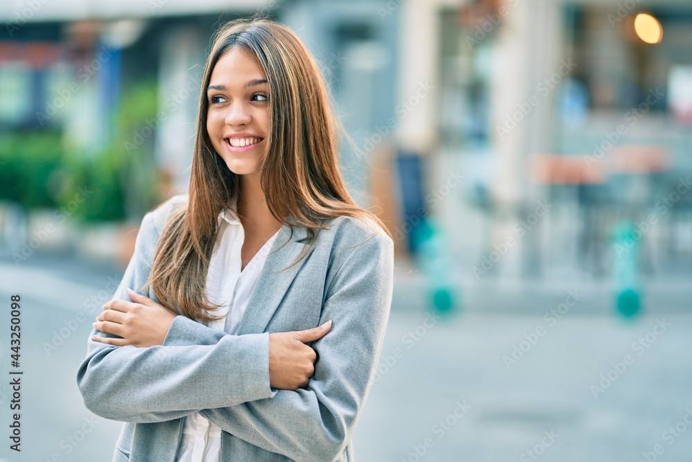 Fototapeta premium Young latin businesswoman with crossed arms smiling happy at the city.