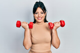 Young hispanic woman wearing sportswear using dumbbells smiling with a happy and cool smile on face. showing teeth.