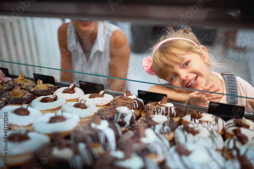 Mother and daughter buying mouth-watering donuts together