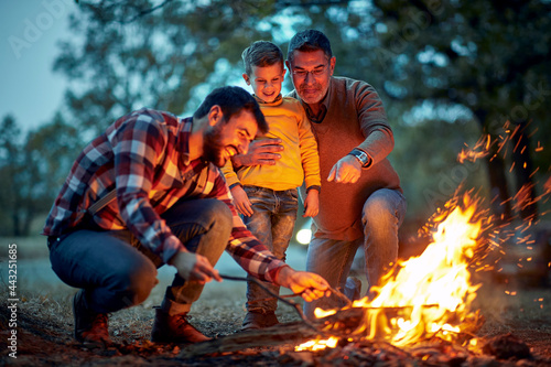 Grandfather and father in the forest showing to grandson how to light up a campfire © luckybusiness