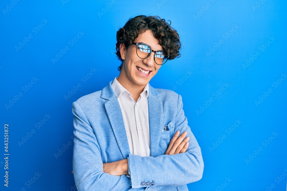 Hispanic young man wearing business jacket and glasses happy face smiling with crossed arms looking at the camera. positive person. Hispanic young man wearing business jacket and glasses happy face smiling with crossed arms looking at the camera. positive person.