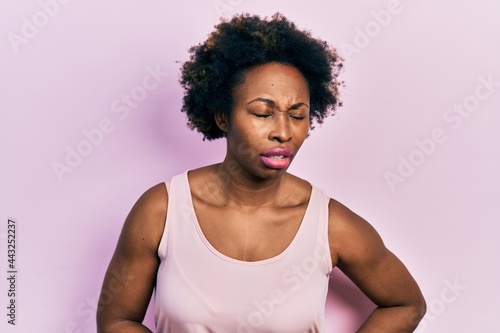 Young african american woman wearing casual sleeveless t shirt with hand on stomach because indigestion, painful illness feeling unwell. ache concept.