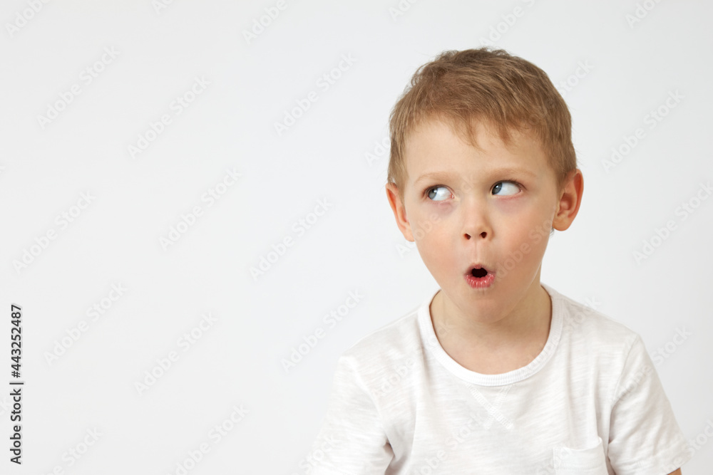 Small boy with blue eyes opened his mouth in surprise at the white background. Child has such an expression on his face wow Small boy with blue eyes opened his mouth in surprise at the white background. Child has such an expression on his face wow