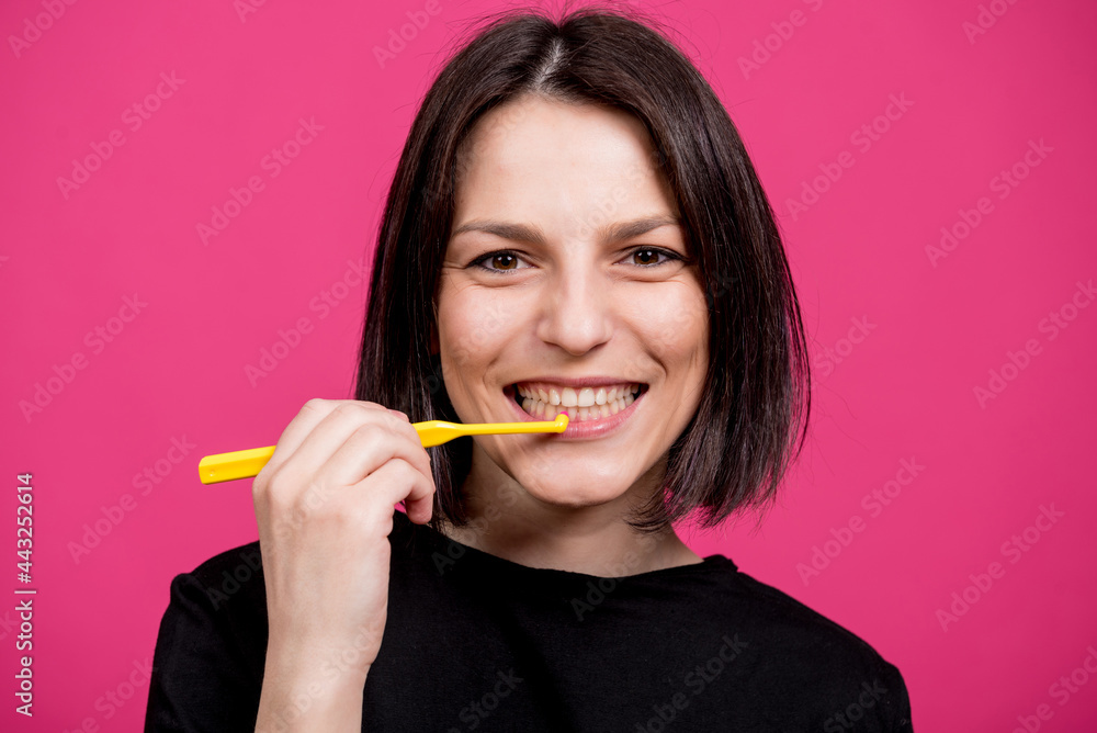 Beautiful happy young woman with single tufted toothbrush on blank pink background Beautiful happy young woman with single tufted toothbrush on blank pink background