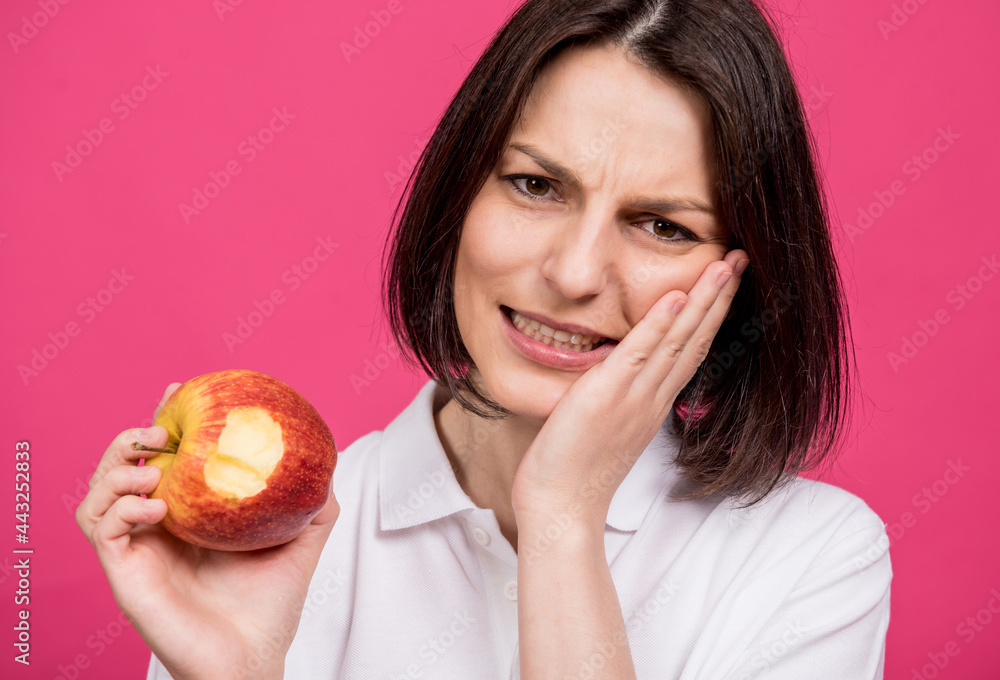 Beautiful young woman bites a big apple and has a toothache Beautiful young woman bites a big apple and has a toothache