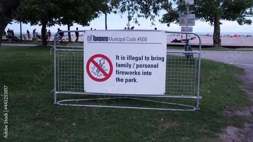 Woodbine Beach at lake. City sign, It is illegal to bring family or personal fireworks into the park. People walking on background. No shooting of fireworks. photo