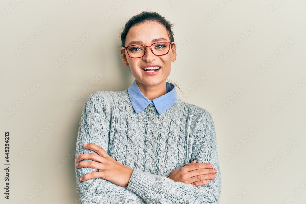 Young caucasian woman wearing casual clothes and glasses happy face smiling with crossed arms looking at the camera. positive person. Young caucasian woman wearing casual clothes and glasses happy face smiling with crossed arms looking at the camera. positive person.