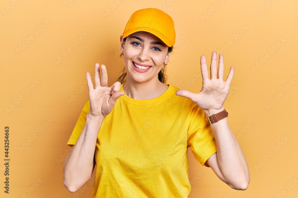 Young hispanic woman wearing delivery uniform and cap showing and pointing up with fingers number eight while smiling confident and happy.