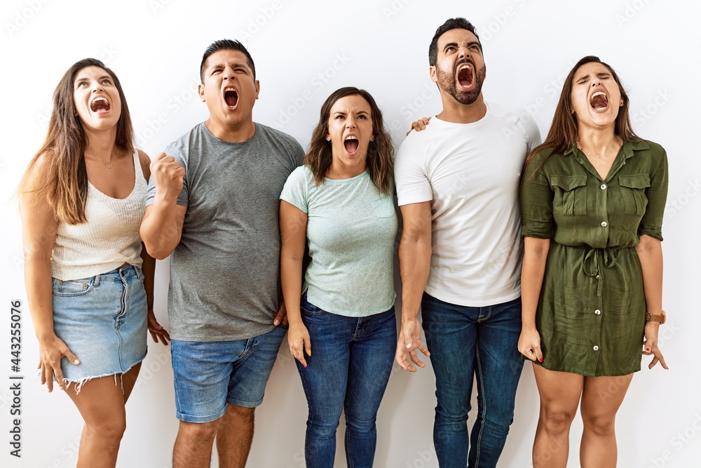 Group of young hispanic friends standing together over isolated background angry and mad screaming frustrated and furious, shouting with anger. rage and aggressive concept. Group of young hispanic friends standing together over isolated background angry and mad screaming frustrated and furious, shouting with anger. rage and aggressive concept.