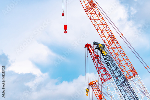 Crawler crane against blue sky and white clouds. Real estate industry. Red crawler crane use reel lift up equipment in construction site. Crane for rent. Crane dealership for construction business. photo