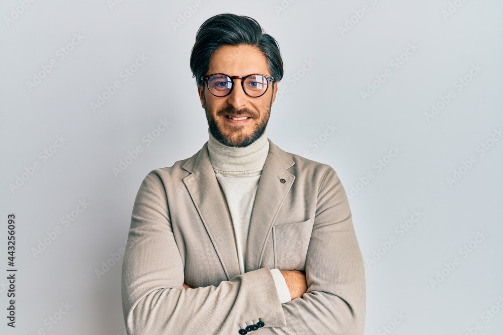 Young hispanic man wearing business jacket and glasses happy face smiling with crossed arms looking at the camera. positive person. Young hispanic man wearing business jacket and glasses happy face smiling with crossed arms looking at the camera. positive person.