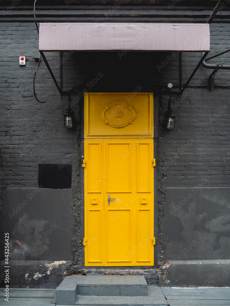 Building with black brick walls and bright yellow door. Colorful urban background. Building with black brick walls and bright yellow door. Colorful urban background.