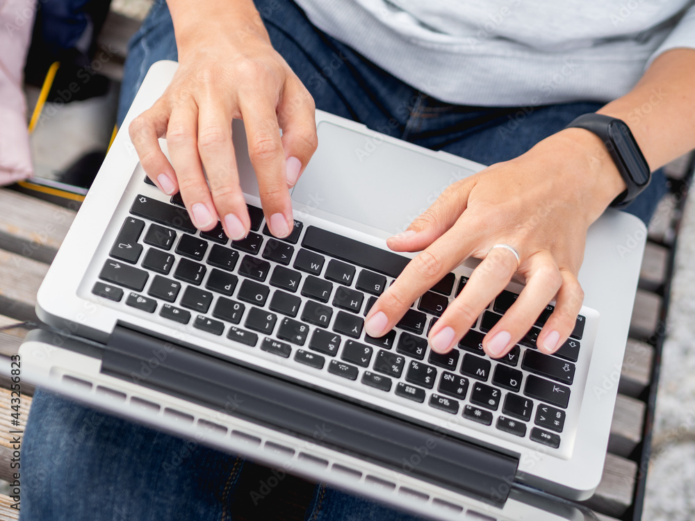 Woman sits with laptop on urban park bench. Freelancer at work. Student learns remotely from outdoors. Modern lifestyle. Woman sits with laptop on urban park bench. Freelancer at work. Student learns remotely from outdoors. Modern lifestyle.