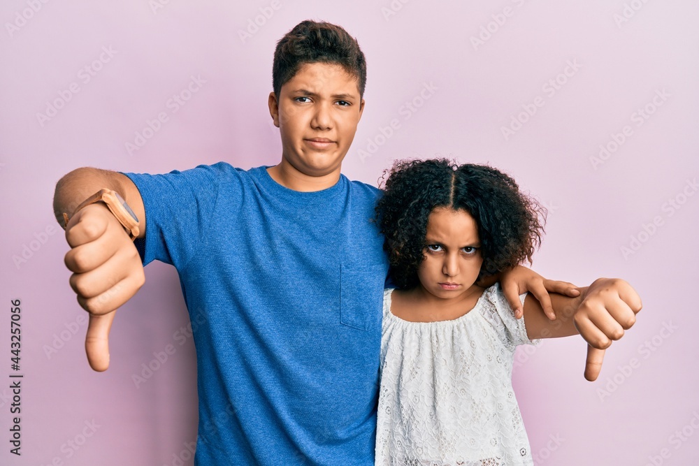 Young hispanic family of brother and sister wearing casual clothes together looking unhappy and angry showing rejection and negative with thumbs down gesture. bad expression. Young hispanic family of brother and sister wearing casual clothes together looking unhappy and angry showing rejection and negative with thumbs down gesture. bad expression.