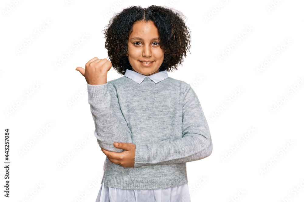 Young little girl with afro hair wearing casual clothes smiling with happy face looking and pointing to the side with thumb up. Young little girl with afro hair wearing casual clothes smiling with happy face looking and pointing to the side with thumb up.
