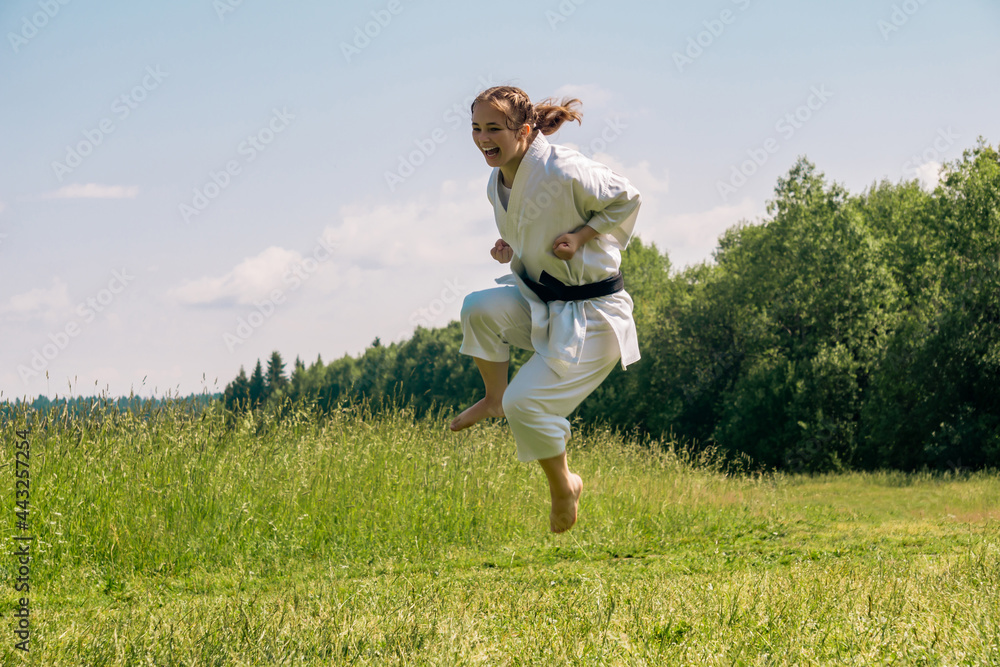 teen girl training karate kata outdoors, performs a kick in a jump teen girl training karate kata outdoors, performs a kick in a jump