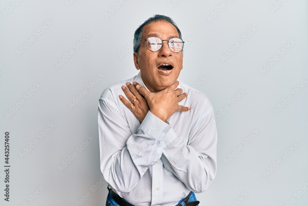 Middle age indian man wearing casual clothes and glasses shouting and suffocate because painful strangle. health problem. asphyxiate and suicide concept. Middle age indian man wearing casual clothes and glasses shouting and suffocate because painful strangle. health problem. asphyxiate and suicide concept.