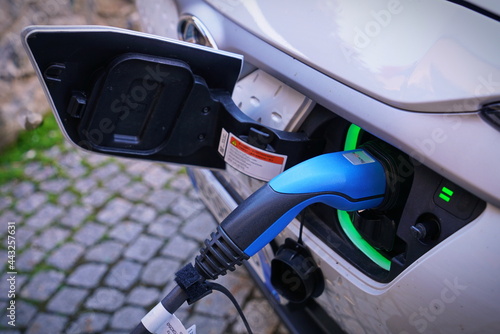 Electric car charging its battery with natural landscape, for green environment, ecology, sustainability, clean air, future. Bolzano, Italy - July 2021