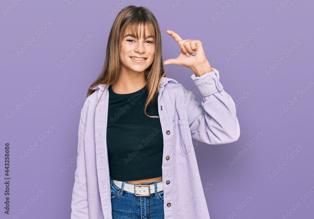 Teenager caucasian girl wearing casual clothes smiling and confident gesturing with hand doing small size sign with fingers looking and the camera. measure concept. Teenager caucasian girl wearing casual clothes smiling and confident gesturing with hand doing small size sign with fingers looking and the camera. measure concept.