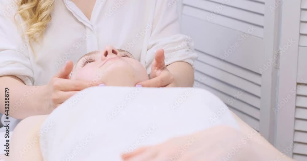 Light facial massage of a young beautiful woman. Pleasant procedure for the beauty and youthful skin in the spa salon Light facial massage of a young beautiful woman. Pleasant procedure for the beauty and youthful skin in the spa salon