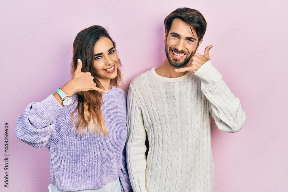 Young hispanic couple wearing casual clothes smiling doing phone gesture with hand and fingers like talking on the telephone. communicating concepts. Young hispanic couple wearing casual clothes smiling doing phone gesture with hand and fingers like talking on the telephone. communicating concepts.
