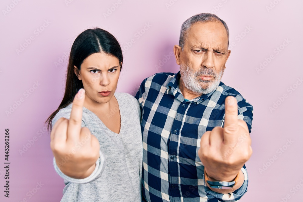 Hispanic father and daughter wearing casual clothes showing middle finger, impolite and rude fuck off expression Hispanic father and daughter wearing casual clothes showing middle finger, impolite and rude fuck off expression