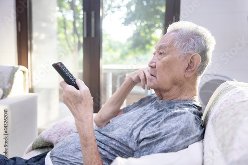 Asian Mature Man Using Television Remote Control in the Living Room