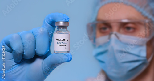 A doctor in medical gloves and a protective mask holds a bottle with coronavirus Covid19 Delta variant strain vaccine.The concept of medicine, healthcare and science.Coronavirus vaccine