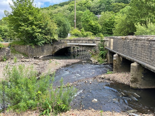 Small river, running alongside the, road, with trees and a bridge by, Burnley Road, Blackshaw, UK