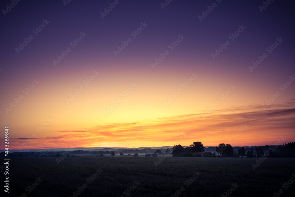 A minimalist landscape of a misty sunrise in summer with a far horizon. Summertime scenery of Northern Europe.