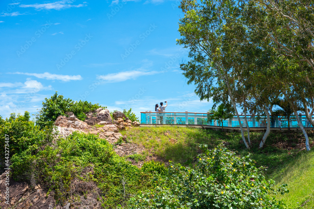 Tourist couple taking pictures at a viewpoint on the mountain There is a beautiful blue sea in the background. Tourist couple taking pictures at a viewpoint on the mountain There is a beautiful blue sea in the background.