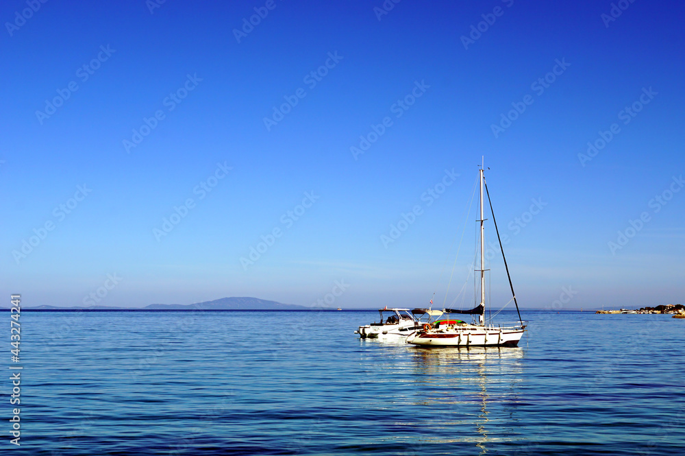 Anchored yacht boats in front of port with background of blue sky and sea Anchored yacht boats in front of port with background of blue sky and sea