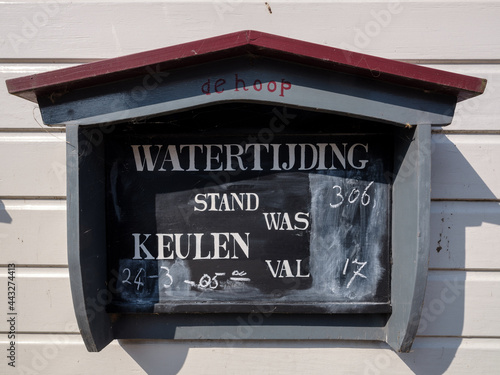 Close-up van het bord met de waterstand bevestigd aan de witte gevel van de Visafslag in de Brabantse vestingstad Woudrichem photo