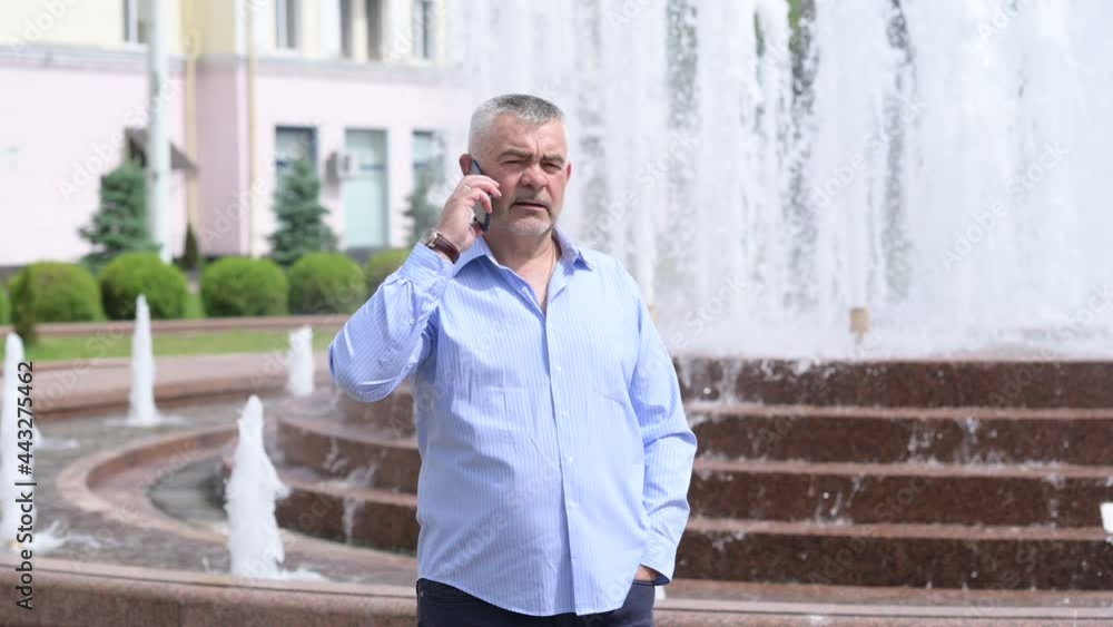 Portrait handsome businessman talking on smartphone at street. Cheerful man man walking with mobile phone at Outside. Portrait handsome businessman talking on smartphone at street. Cheerful man man walking with mobile phone at Outside.
