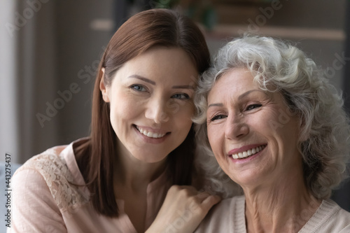 Everything will be ok, mommy. Smiling adult daughter hug shoulders of older mom share optimistic mood look aside dream together. Loving grownup grandkid support hoary granny inspire to believe in good