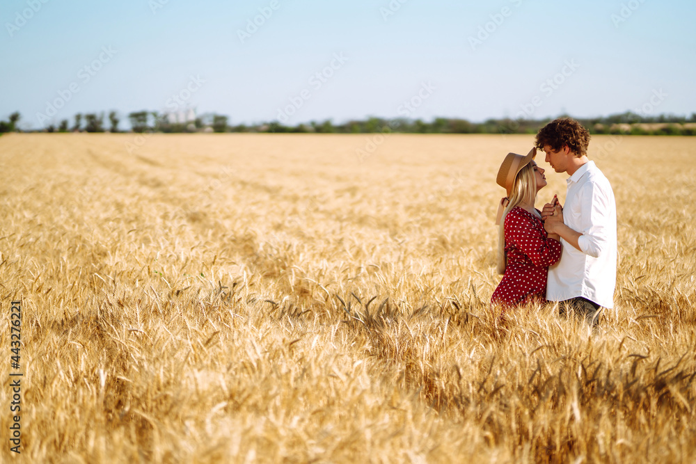 Young happy couple hugging on  a wheat field, on the sunset. Enjoying time together. The concept of youth, love and lifestyle.