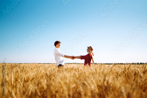 Young happy couple hugging on  a wheat field, on the sunset. Enjoying time together. The concept of youth, love and lifestyle.