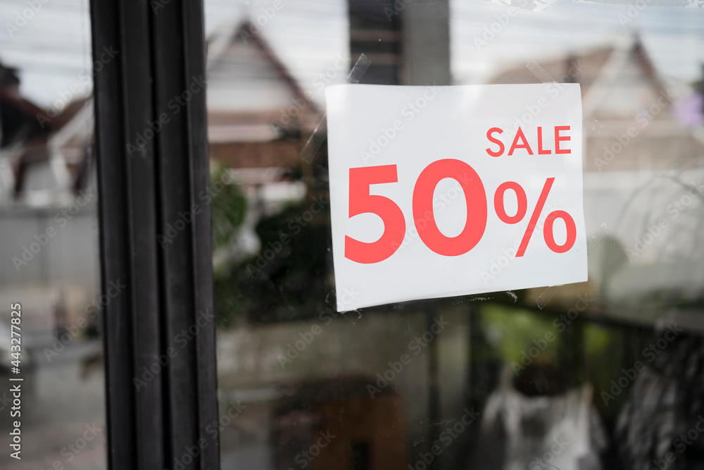 Sale signs in shop window, big reductions.