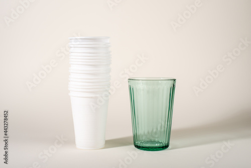 Glass and stack of plastic cups. Glass or plastic. Reusable versus disposable.