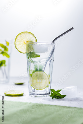 Mojito cocktails served on a bright background with lime and straw