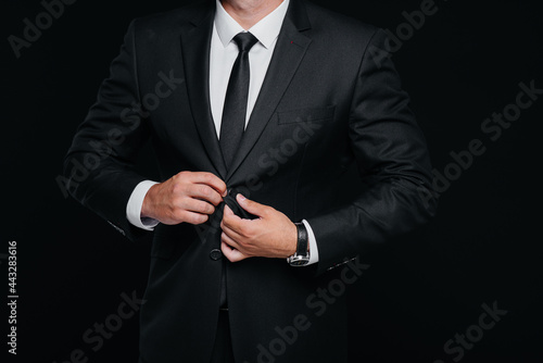A handsome young man wears a stylish black suit and smiles on a black background. Clean up, prepare.
