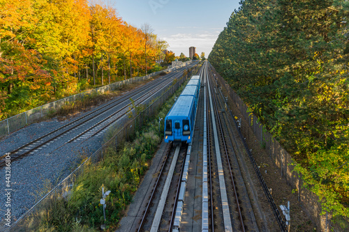 Blue rapid system train passing through the countryside forest of Scarborough, Ontario, Canada photo
