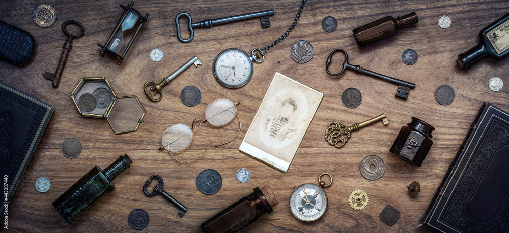 A collection of antique antiques is spread out on the table. Old coins, glasses, photography, glass bottles, keys, watch and compass. Vintage collection. History background. A collection of antique antiques is spread out on the table. Old coins, glasses, photography, glass bottles, keys, watch and compass. Vintage collection. History background.