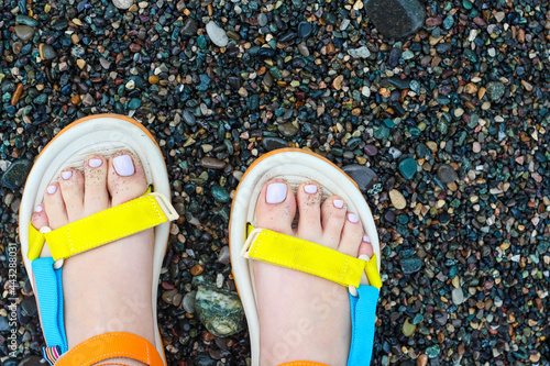 Women's feet in colorful sandals at the beach. Summer vacation and travel idea photo