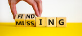 Finding or missing symbol. Businessman turns wooden cubes and changes the word missing to finding. Beautiful yellow table, white background. Business, finding or missing concept. Copy space.