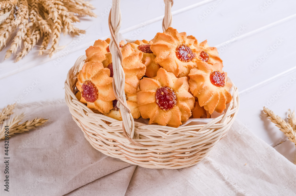 Fresh tasty shortbread cookies stuffed with jam in a wicker basket on a wooden background