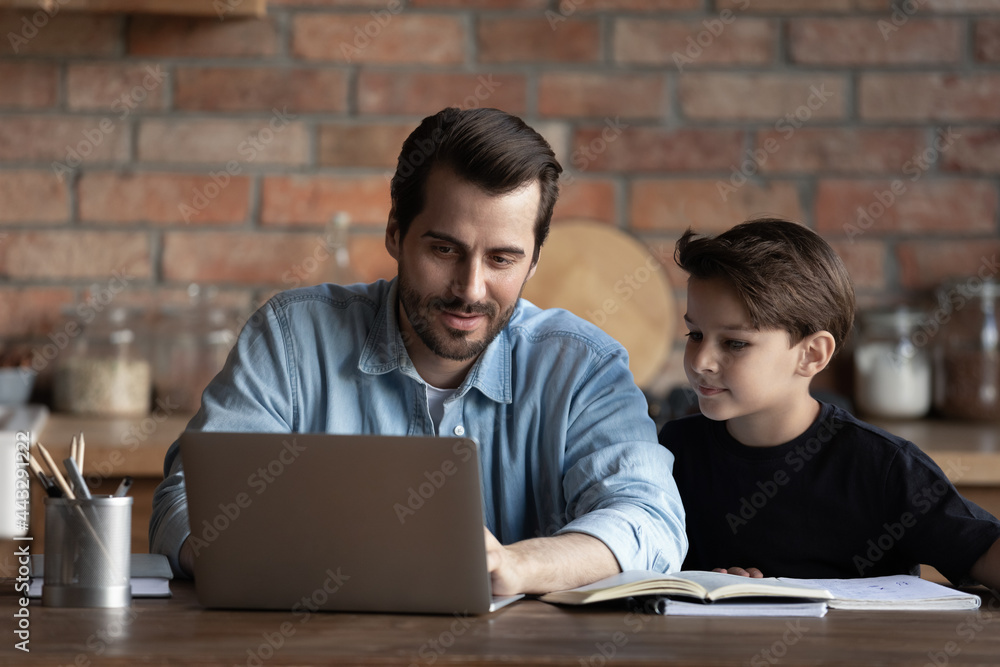 Best dad helping schoolboy son, explaining school homework to child. Father and kid using laptop at table together, watching learning webinar, online virtual lesson. Family support, homeschool concept Best dad helping schoolboy son, explaining school homework to child. Father and kid using laptop at table together, watching learning webinar, online virtual lesson. Family support, homeschool concept