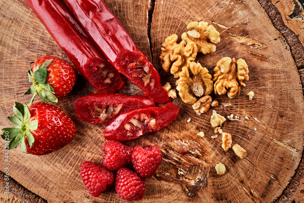 slicing Churchkhela, strawberries and nuts on a wooden background, top view, serving slicing Churchkhela, strawberries and nuts on a wooden background, top view, serving